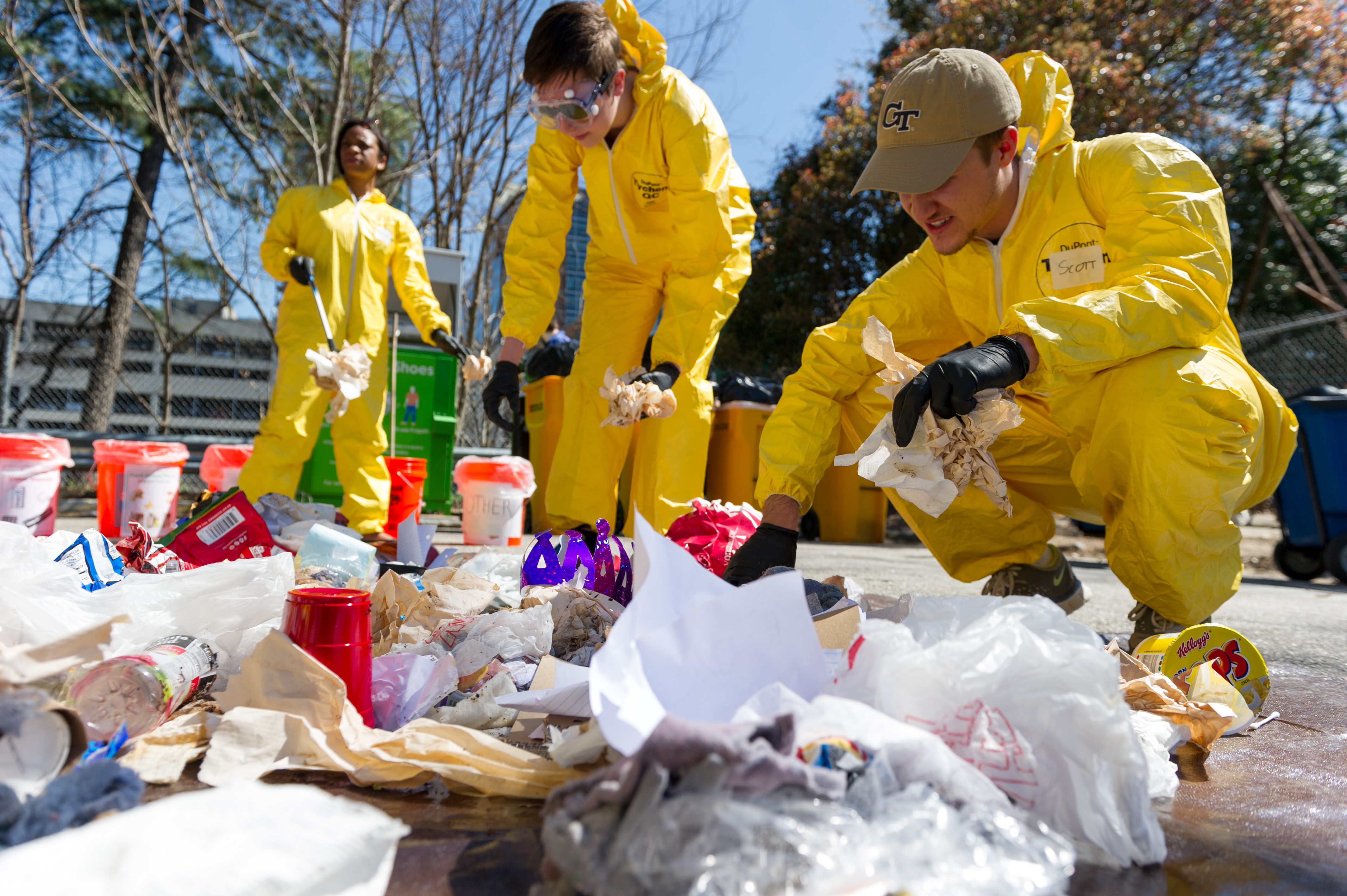 students in a yellow suit picking up trash