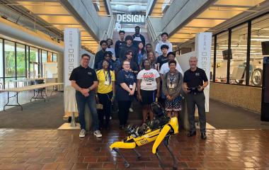 students pose with a robotic dog on stairs