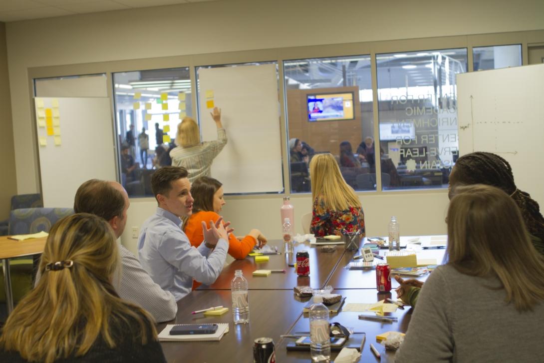 OUE staff sit around a table near a whiteboard