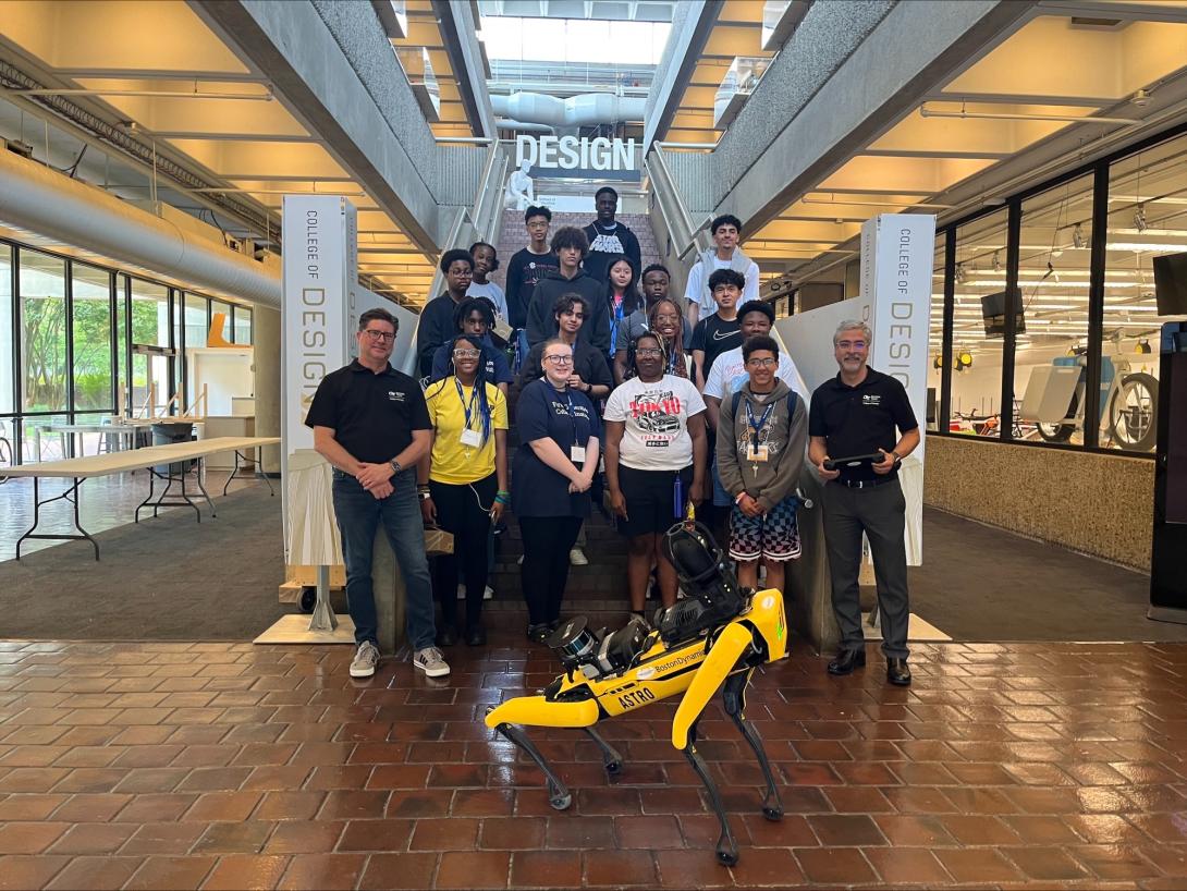 students pose with a robotic dog on stairs