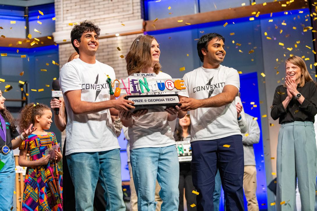 Winning team, Convexity Electronics, holds InVenture Prize first place trophy onstage.